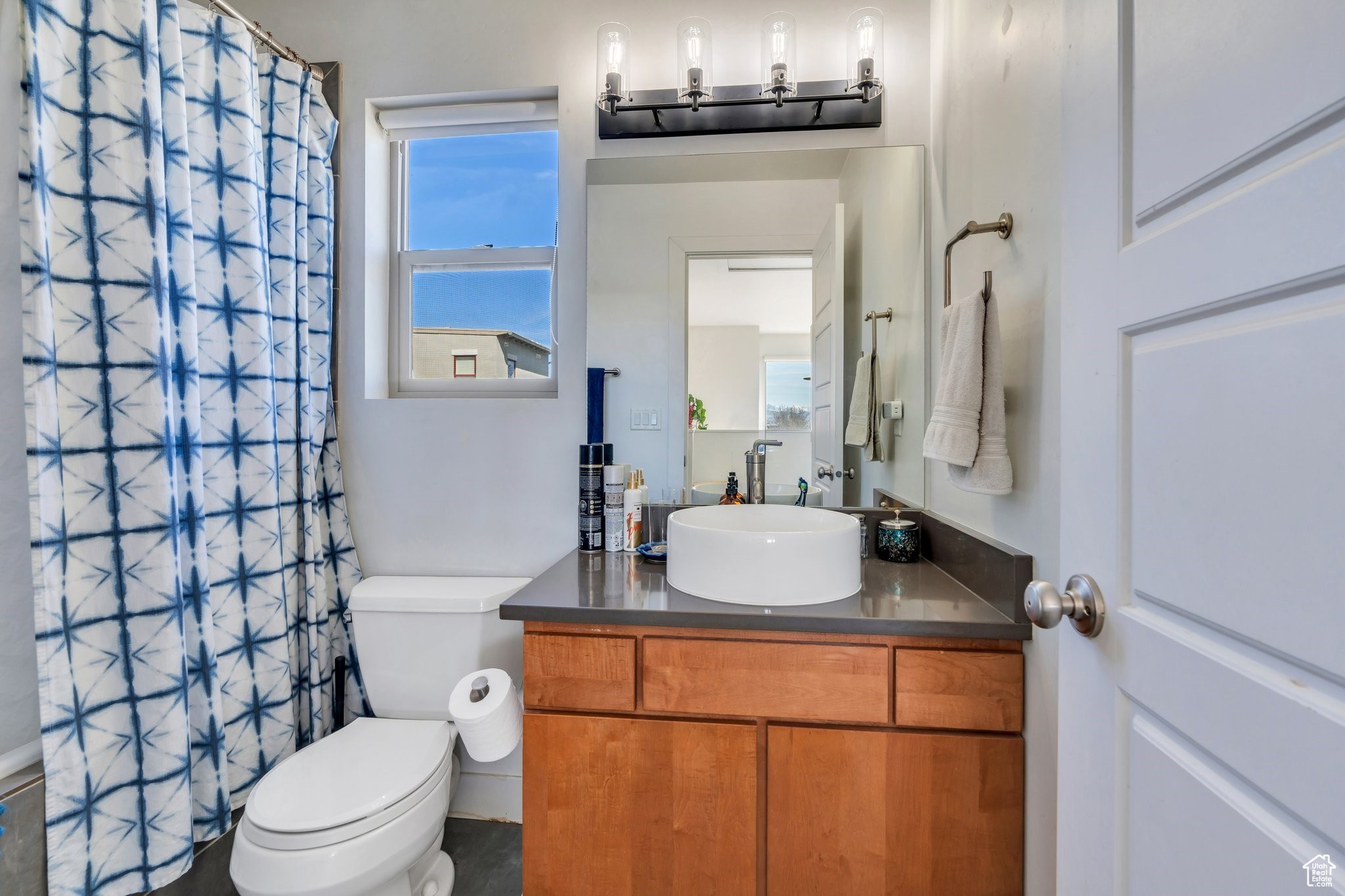 Full bathroom with a wealth of natural light, curtained shower, toilet, and vanity