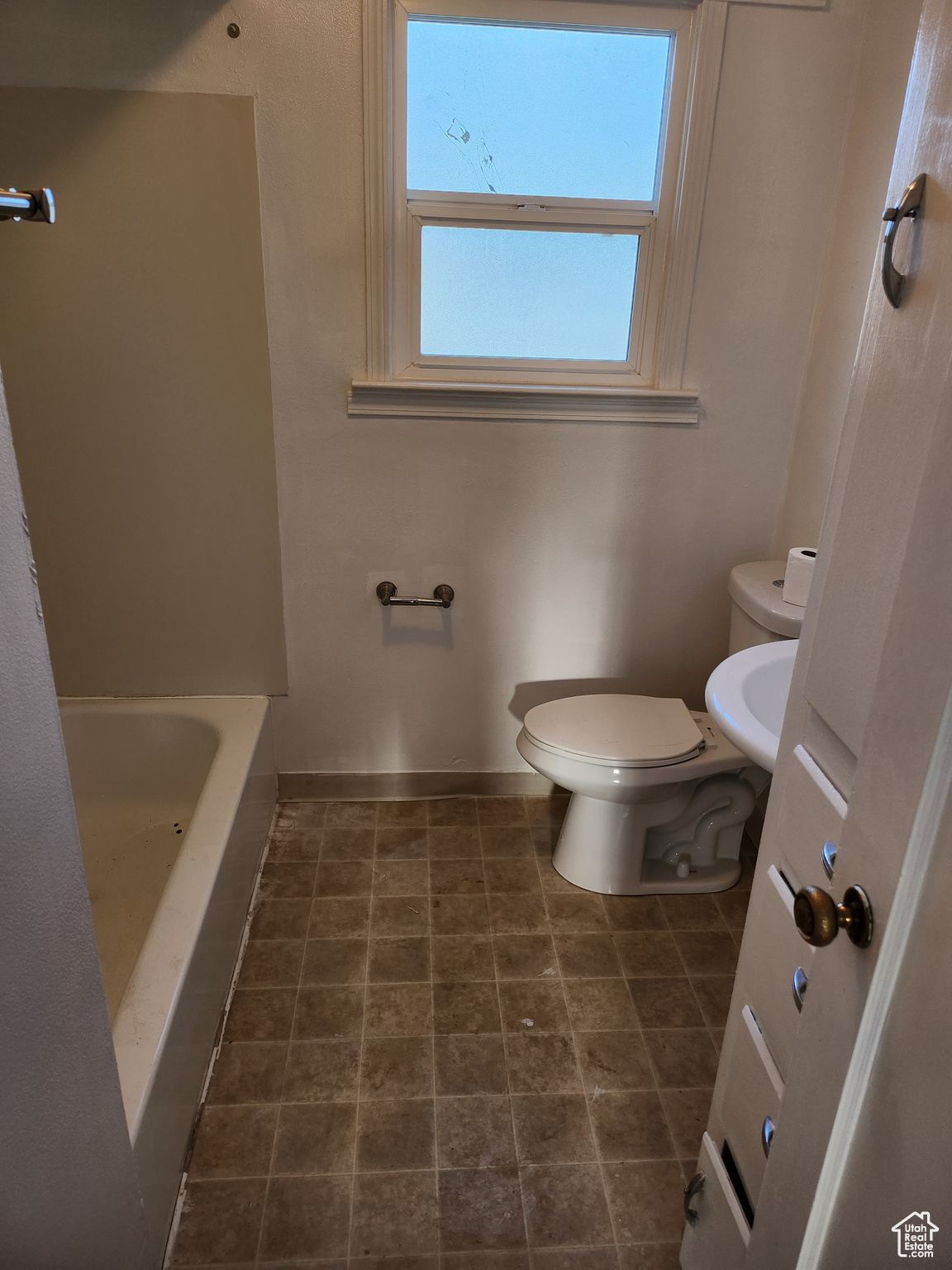 Bathroom with a bathtub, toilet, and baseboards