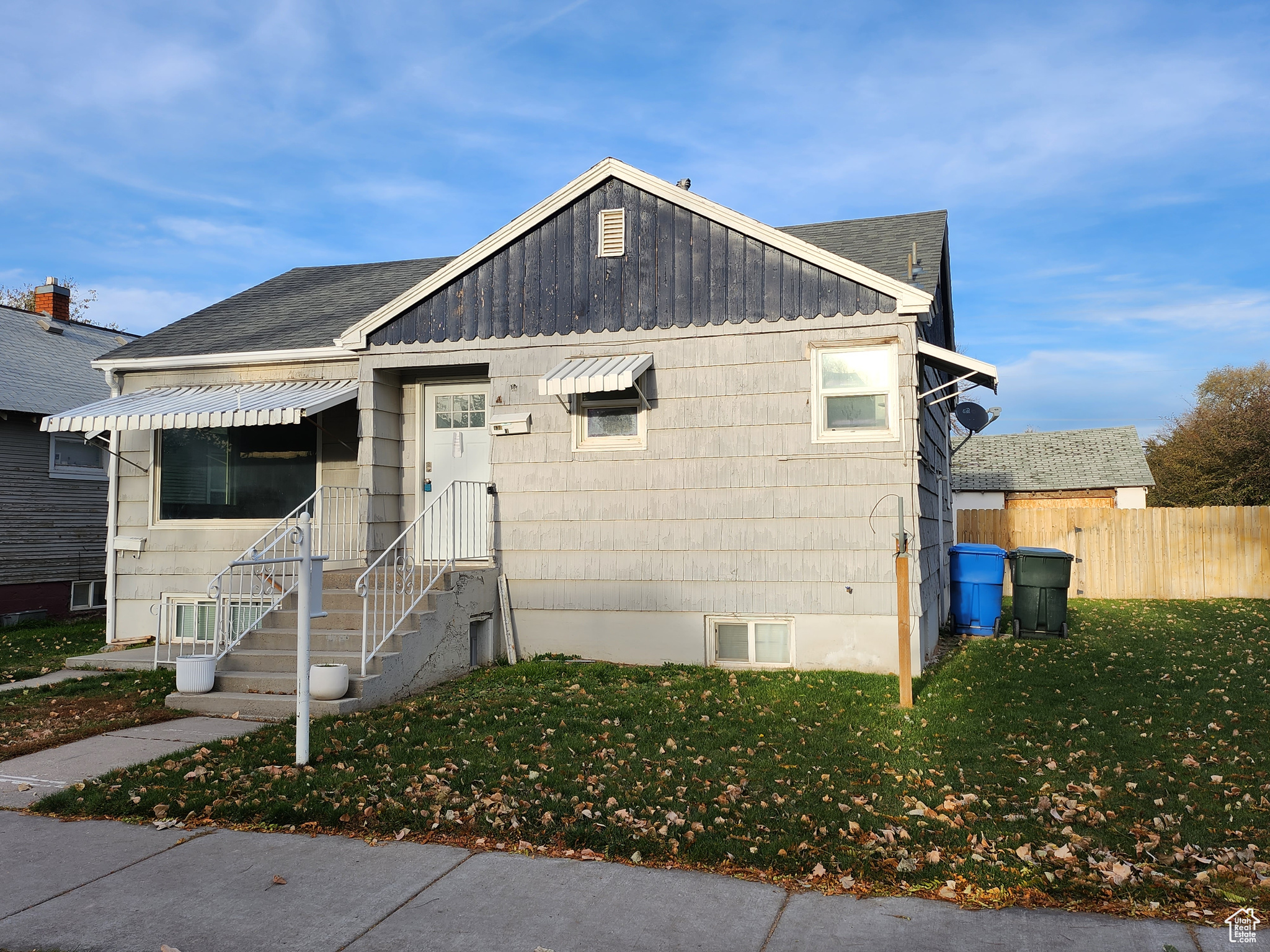 Bungalow with a front lawn, fence, and a shingled roof