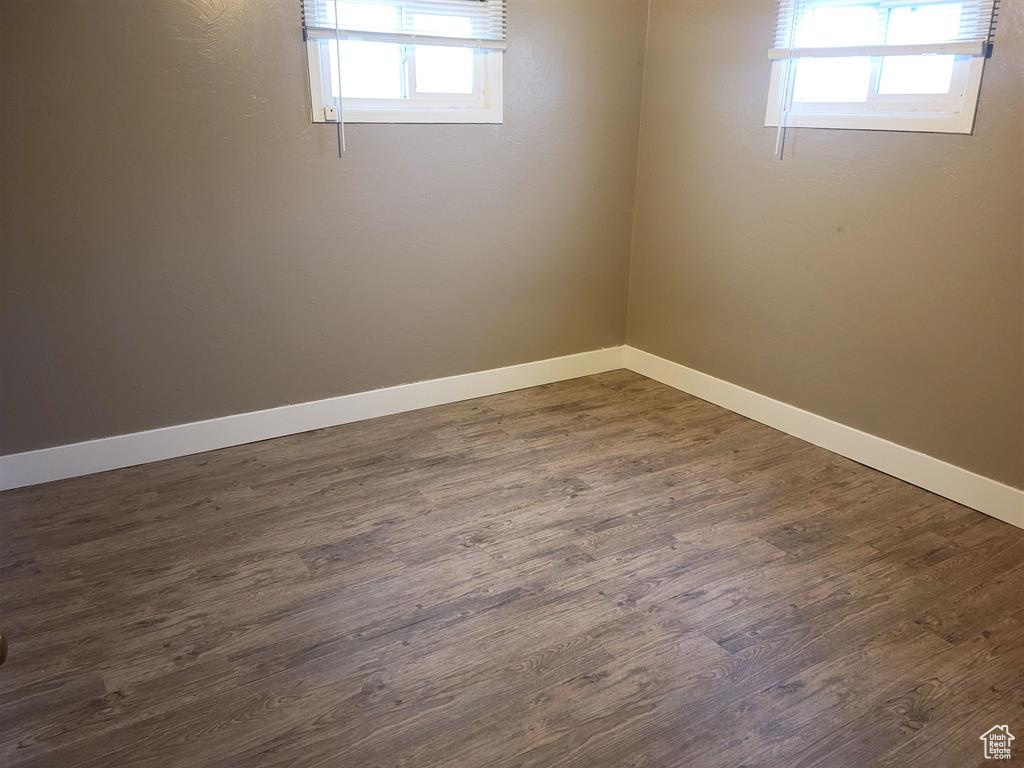 Spare room featuring a wealth of natural light, baseboards, and dark wood finished floors