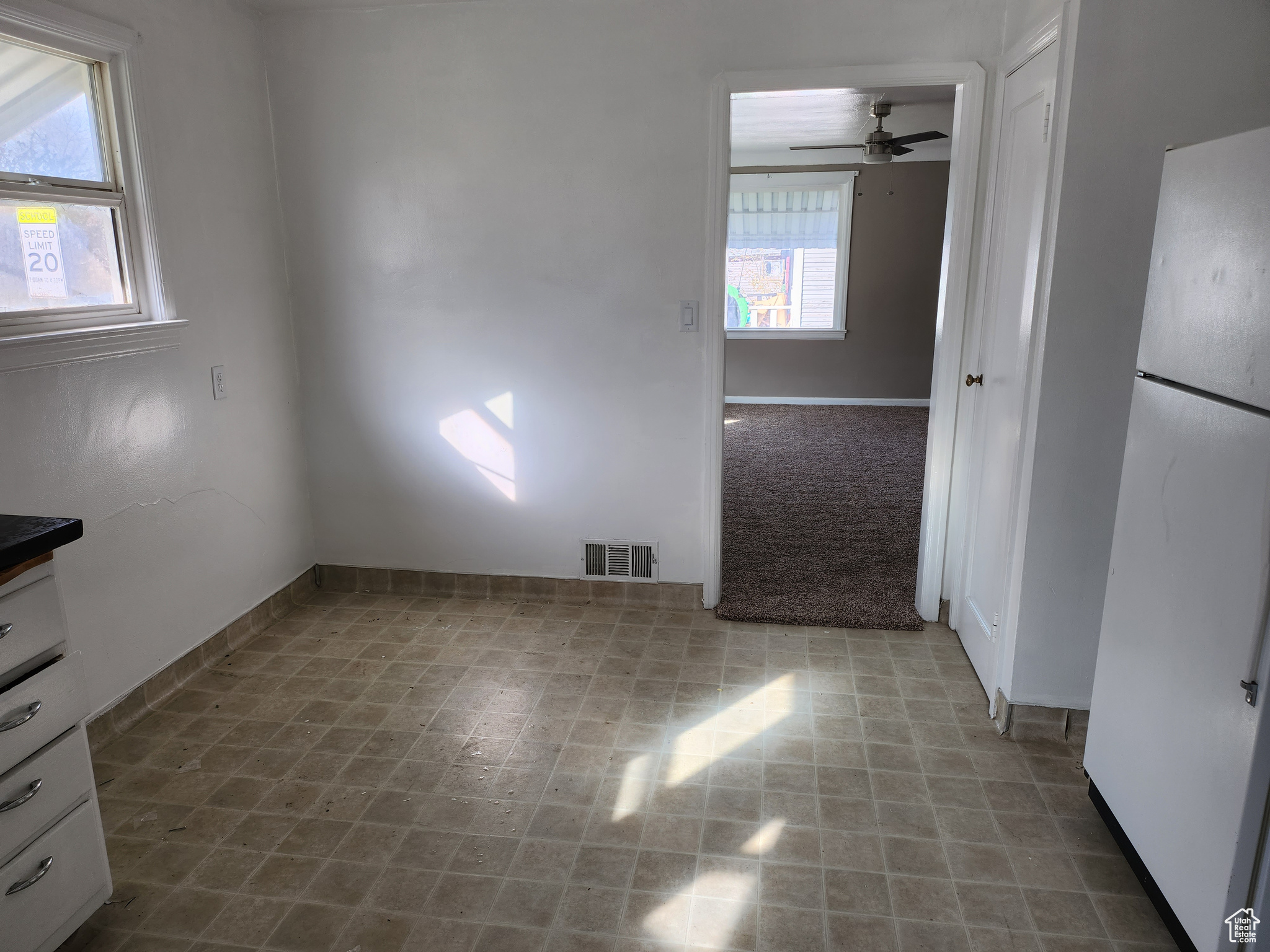 Empty room featuring visible vents, carpet floors, and ceiling fan