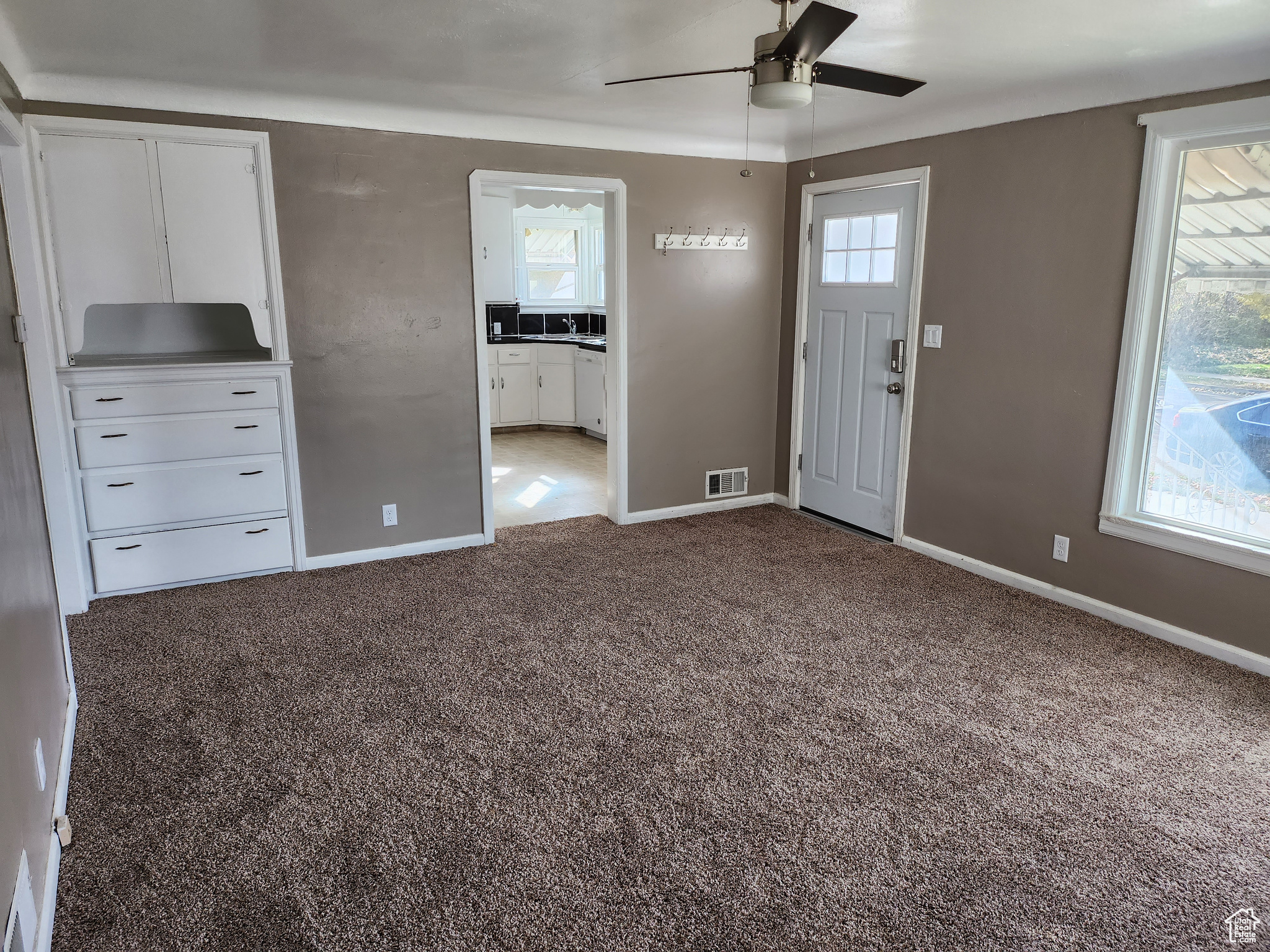 Carpeted entryway featuring visible vents, baseboards, and ceiling fan