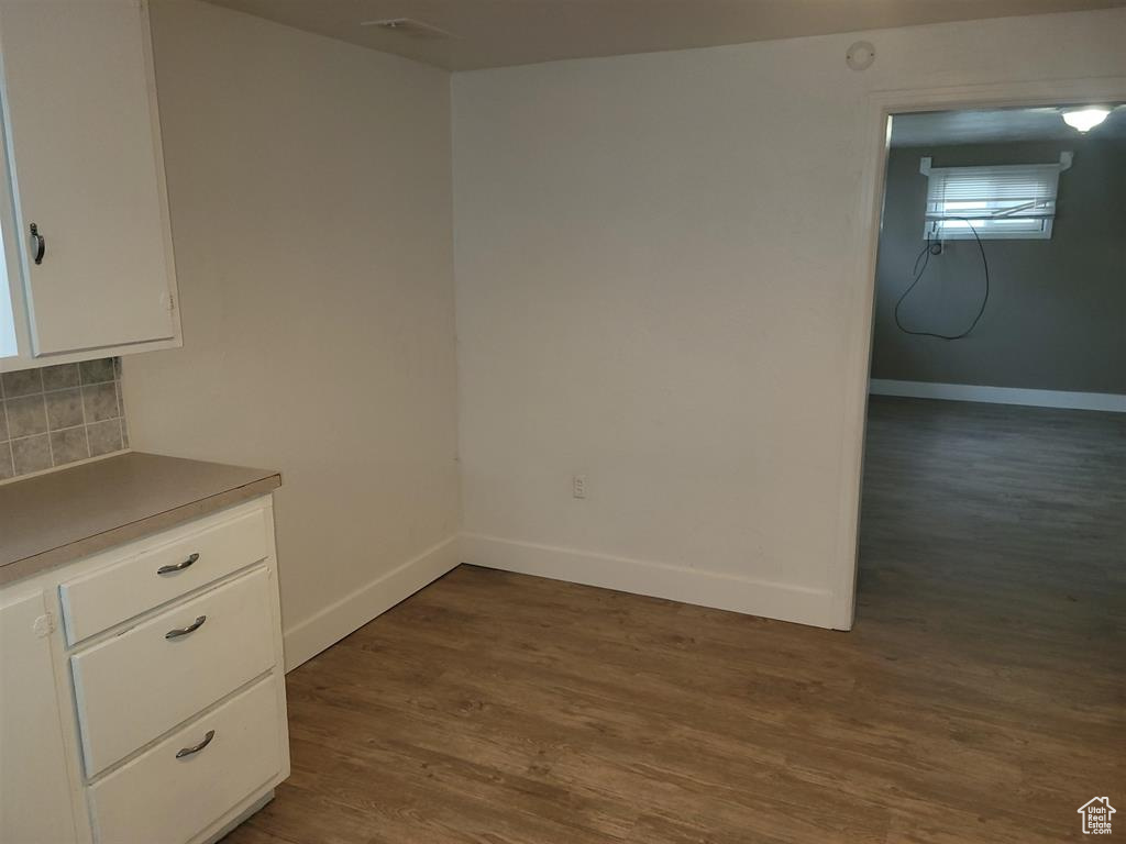 Unfurnished dining area with dark wood finished floors and baseboards