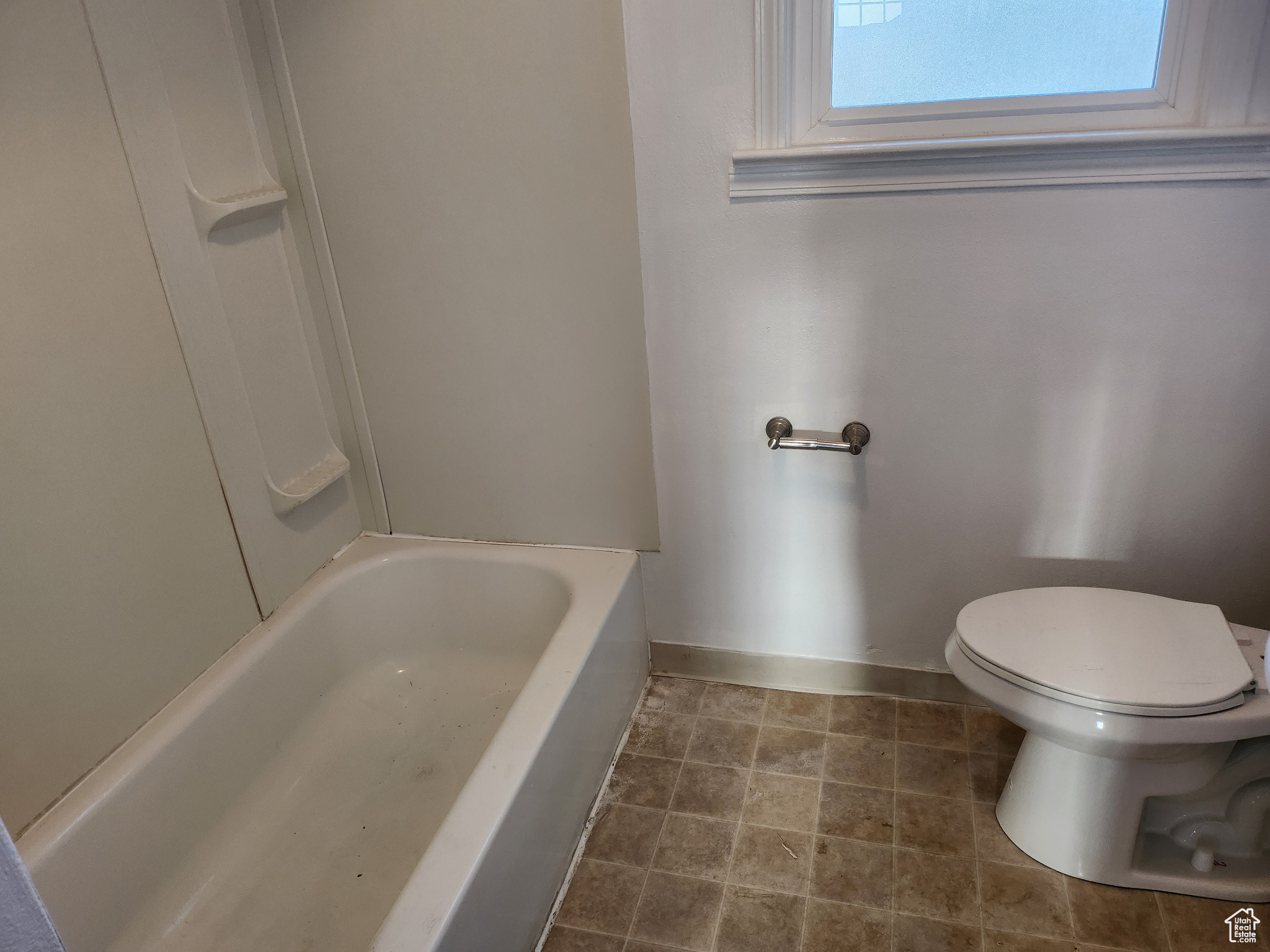 Bathroom featuring toilet, a bathtub, and baseboards