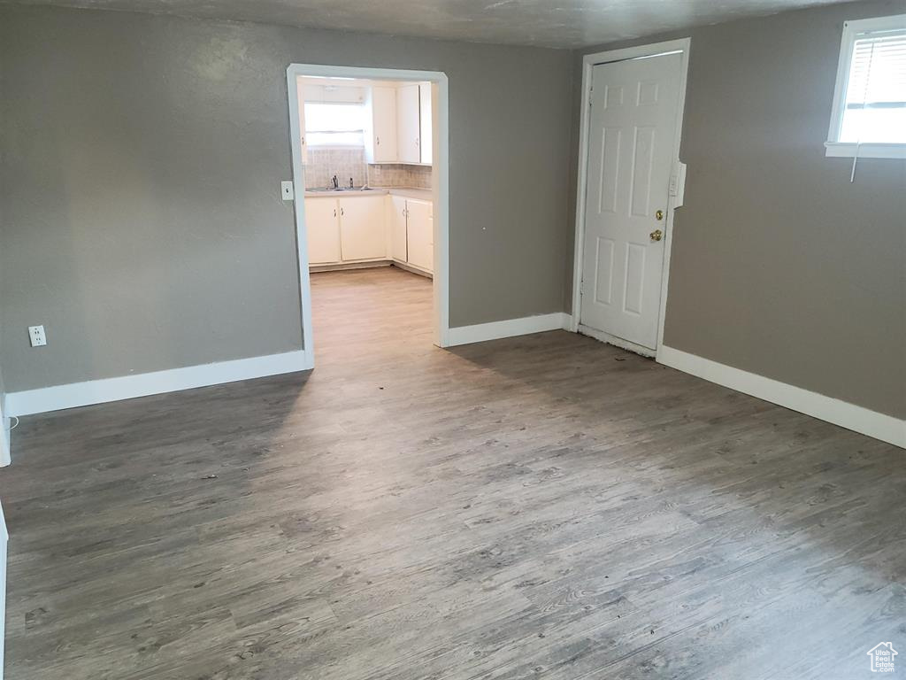 Empty room with a sink, baseboards, and wood finished floors