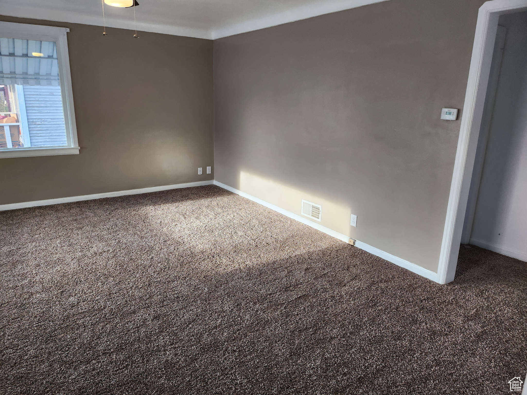 Carpeted empty room with visible vents and baseboards