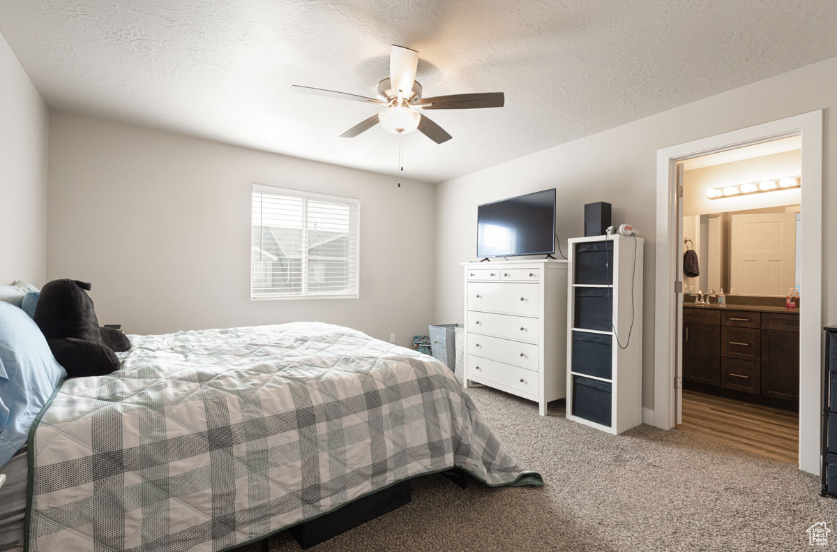 Bedroom with carpet, ensuite bath, and a textured ceiling