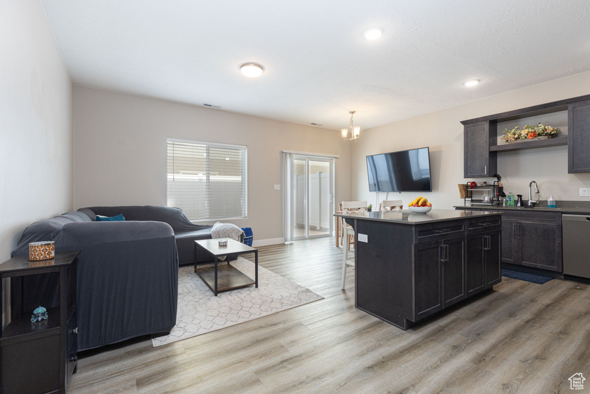 Kitchen featuring a kitchen island, a breakfast bar, LVP flooring, stainless steel dishwasher, and open floor plan