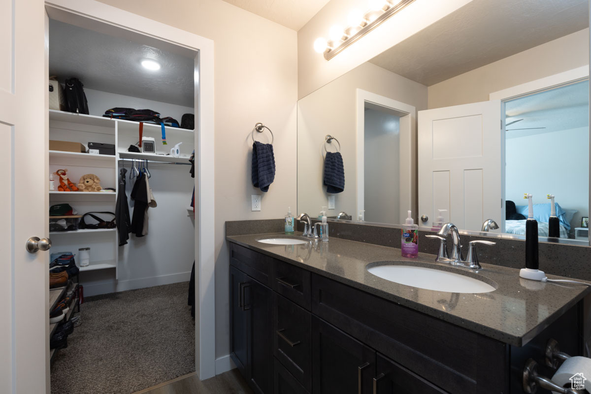 Full master bathroom featuring a spacious closet, double vanity, baseboards, and a sink