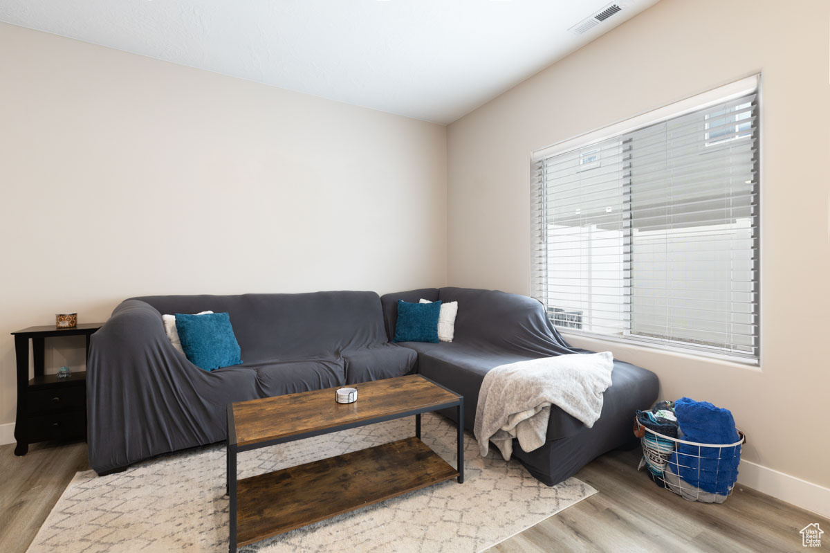 Living room with visible vents, baseboards, and wood finished floors