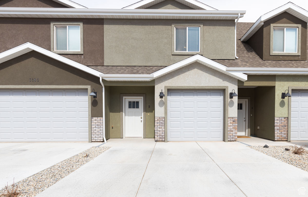 Townhome / multi-family property featuring brick siding, stucco siding, concrete driveway, and a garage