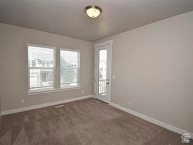 Unfurnished room featuring baseboards and dark carpet