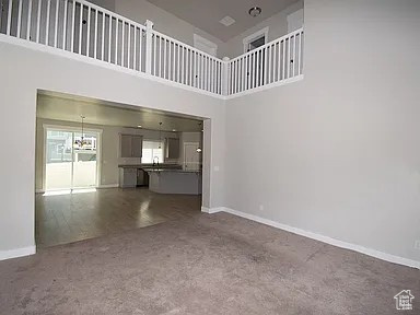 Unfurnished living room featuring baseboards and a high ceiling