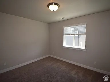 Empty room with baseboards and dark colored carpet