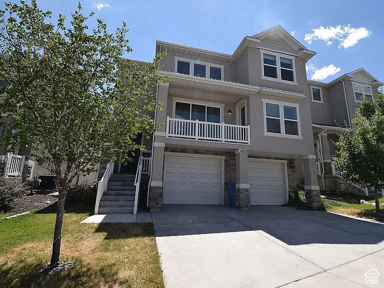 View of front of property featuring stone siding, stucco siding, an attached garage, and concrete driveway