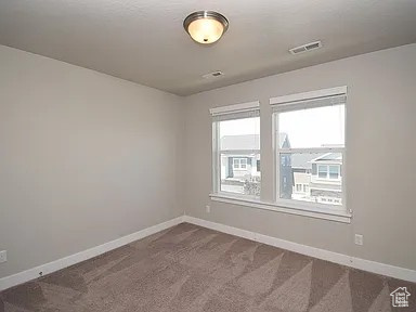 Unfurnished room with visible vents, dark carpet, and baseboards