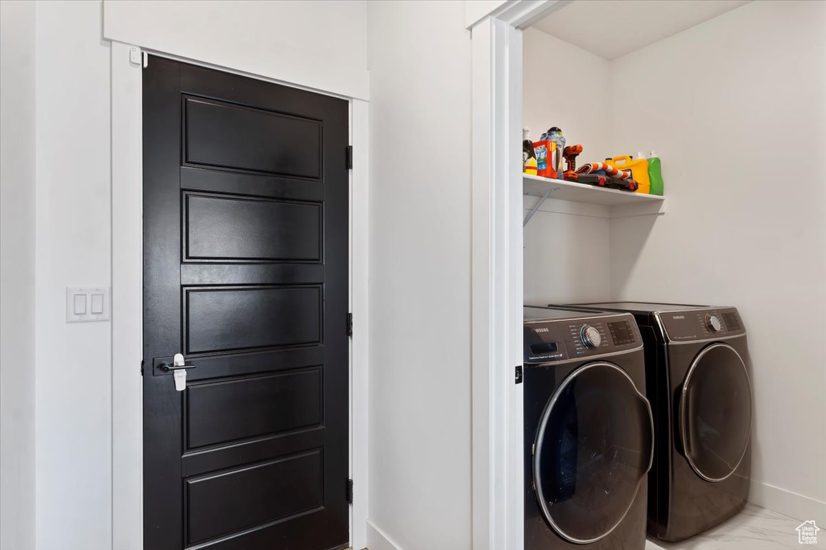 Washroom with washer and clothes dryer, laundry area, marble finish floor, and baseboards