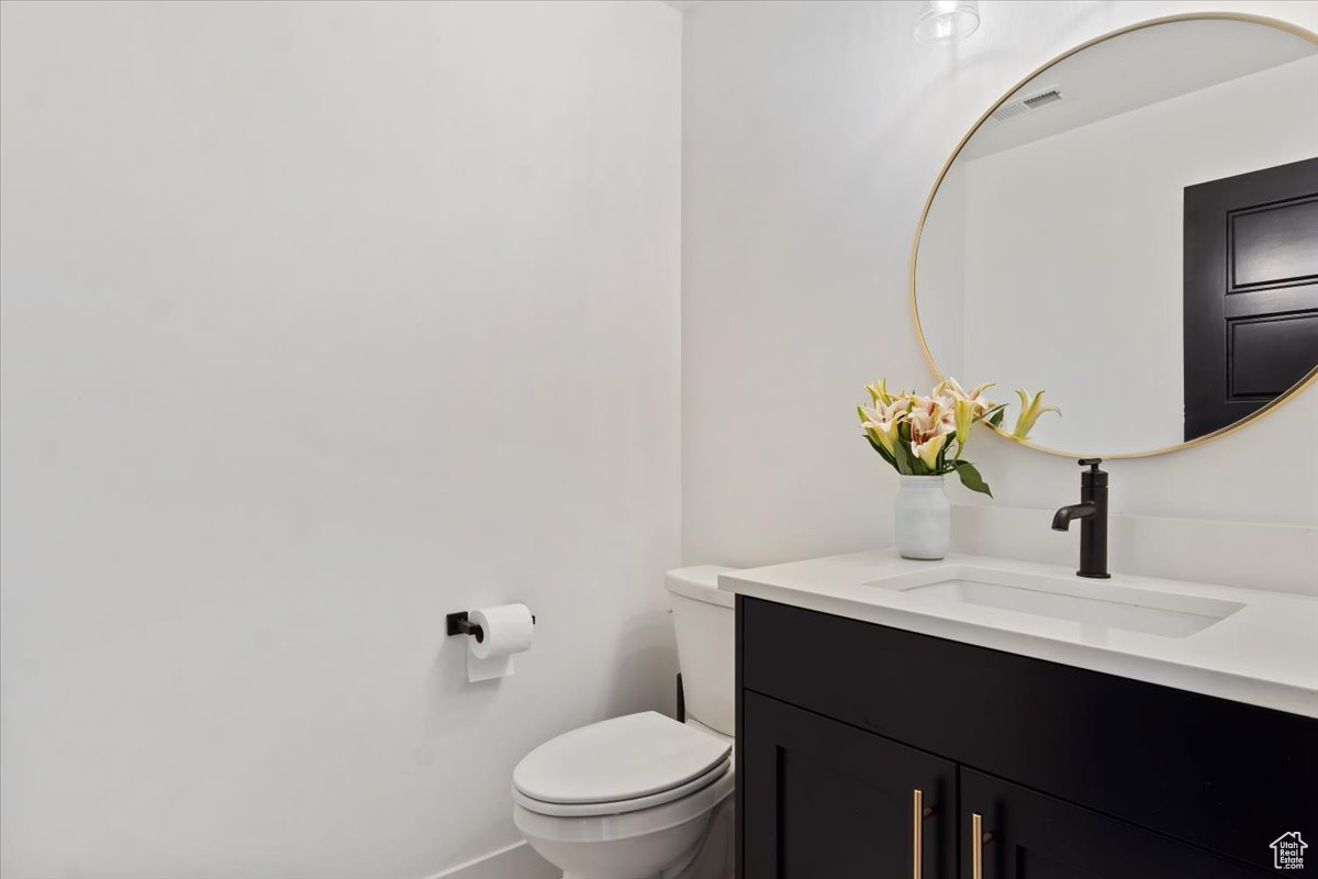 Half bath featuring visible vents, toilet, and vanity