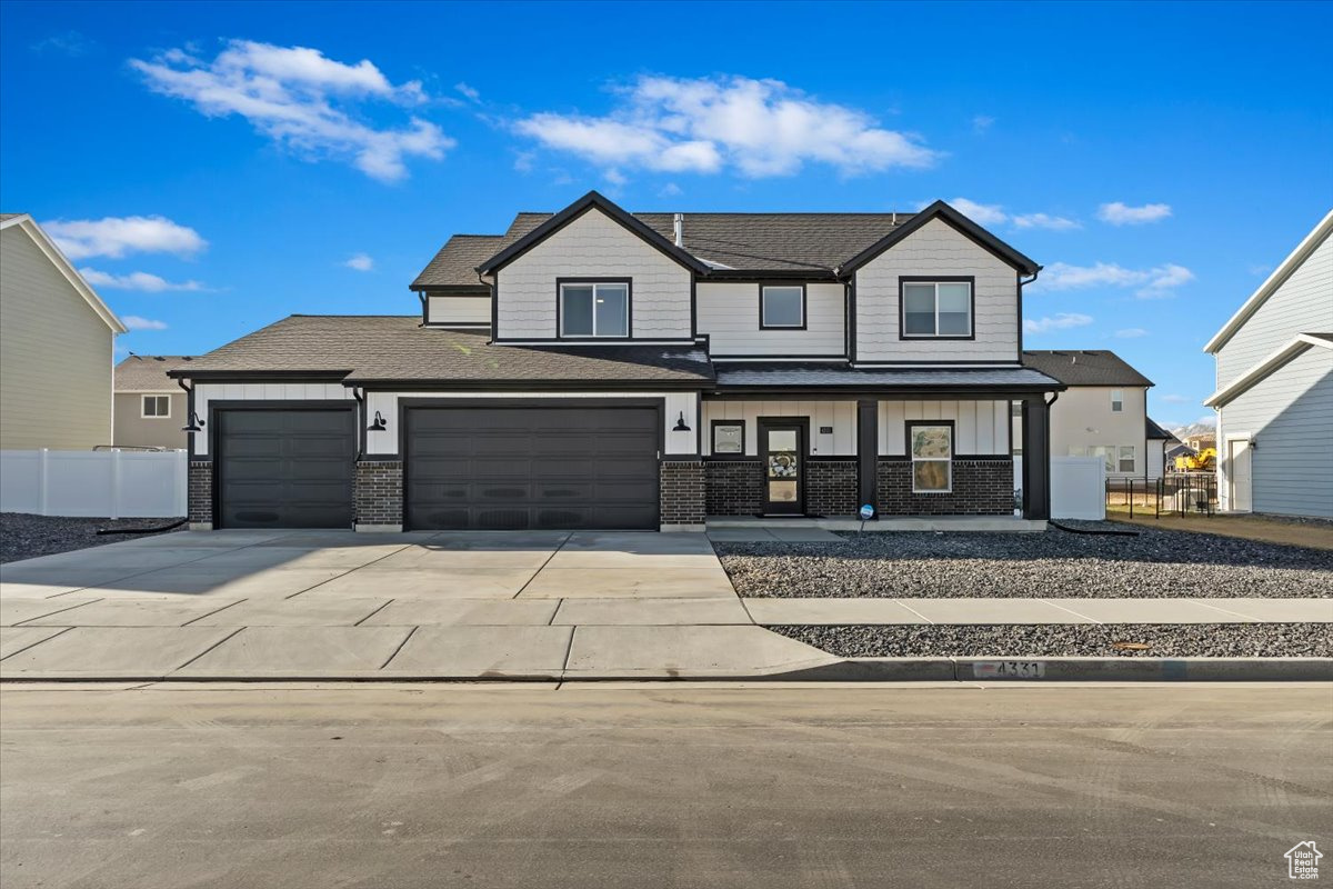 Modern farmhouse featuring fence, a porch, concrete driveway, board and batten siding, and brick siding