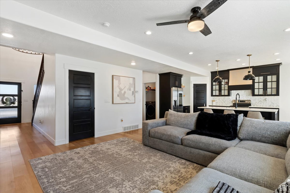 Living room featuring visible vents, light wood finished floors, baseboards, washer / dryer, and recessed lighting