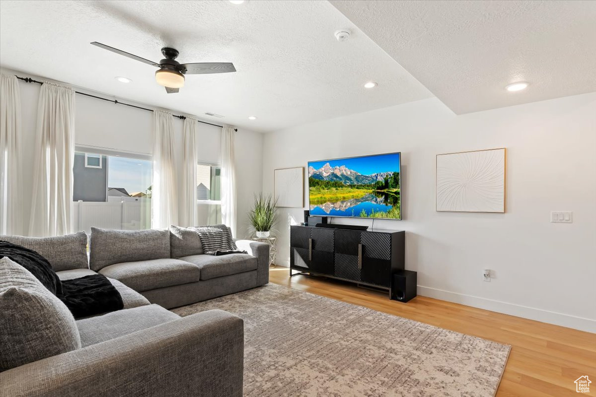 Living room featuring light wood-style flooring, recessed lighting, baseboards, and a textured ceiling