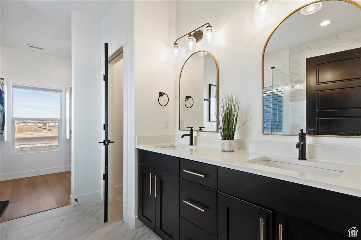 Bathroom with double vanity, visible vents, marble finish floor, and a sink