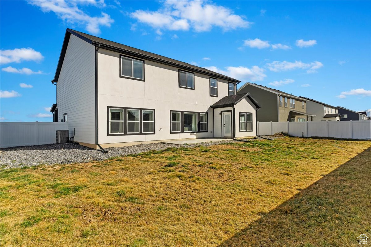 Rear view of house featuring central AC unit, a yard, a fenced backyard, and an outdoor structure