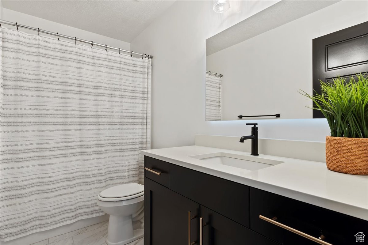 Bathroom featuring toilet, marble finish floor, and vanity