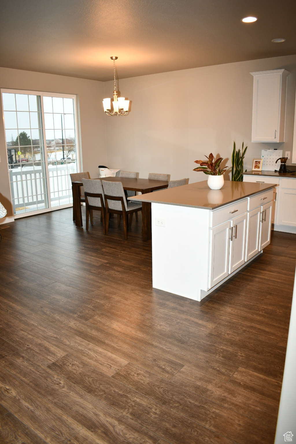 Kitchen with dark wood-style floors, pendant lighting, white cabinets, and a chandelier
