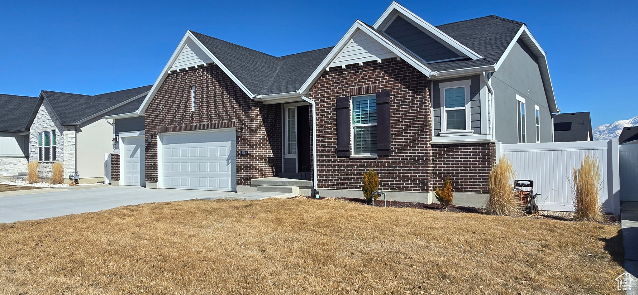View of front facade featuring a front lawn, concrete driveway, brick siding, and an attached garage