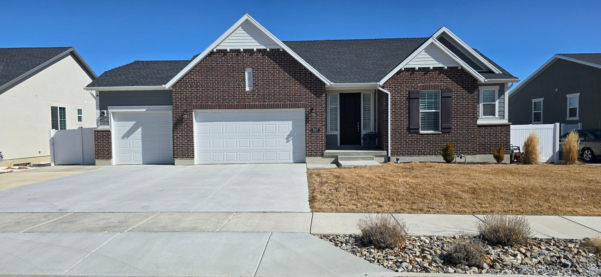 View of front facade with driveway, brick siding, an attached garage, and fence