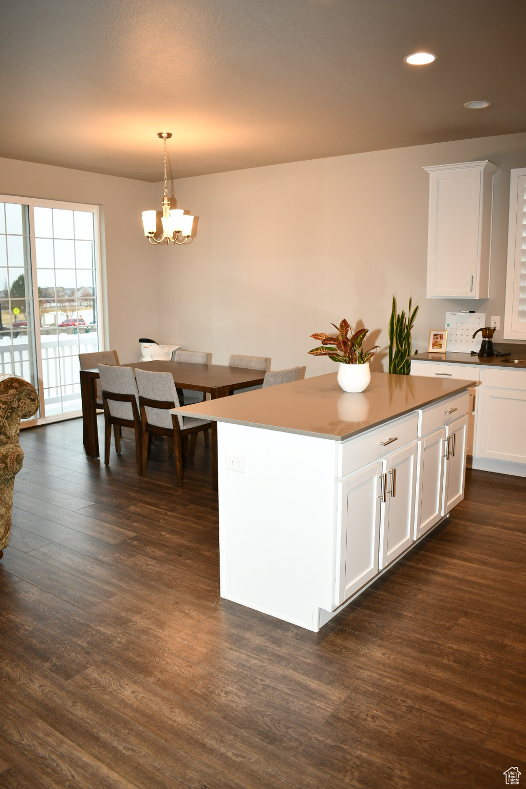 Kitchen featuring dark wood-style floors, a chandelier, white cabinets, and decorative light fixtures