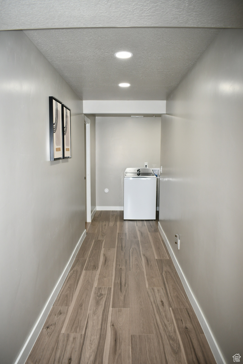 Clothes washing area with a textured ceiling, recessed lighting, wood finished floors, baseboards, and washer / clothes dryer