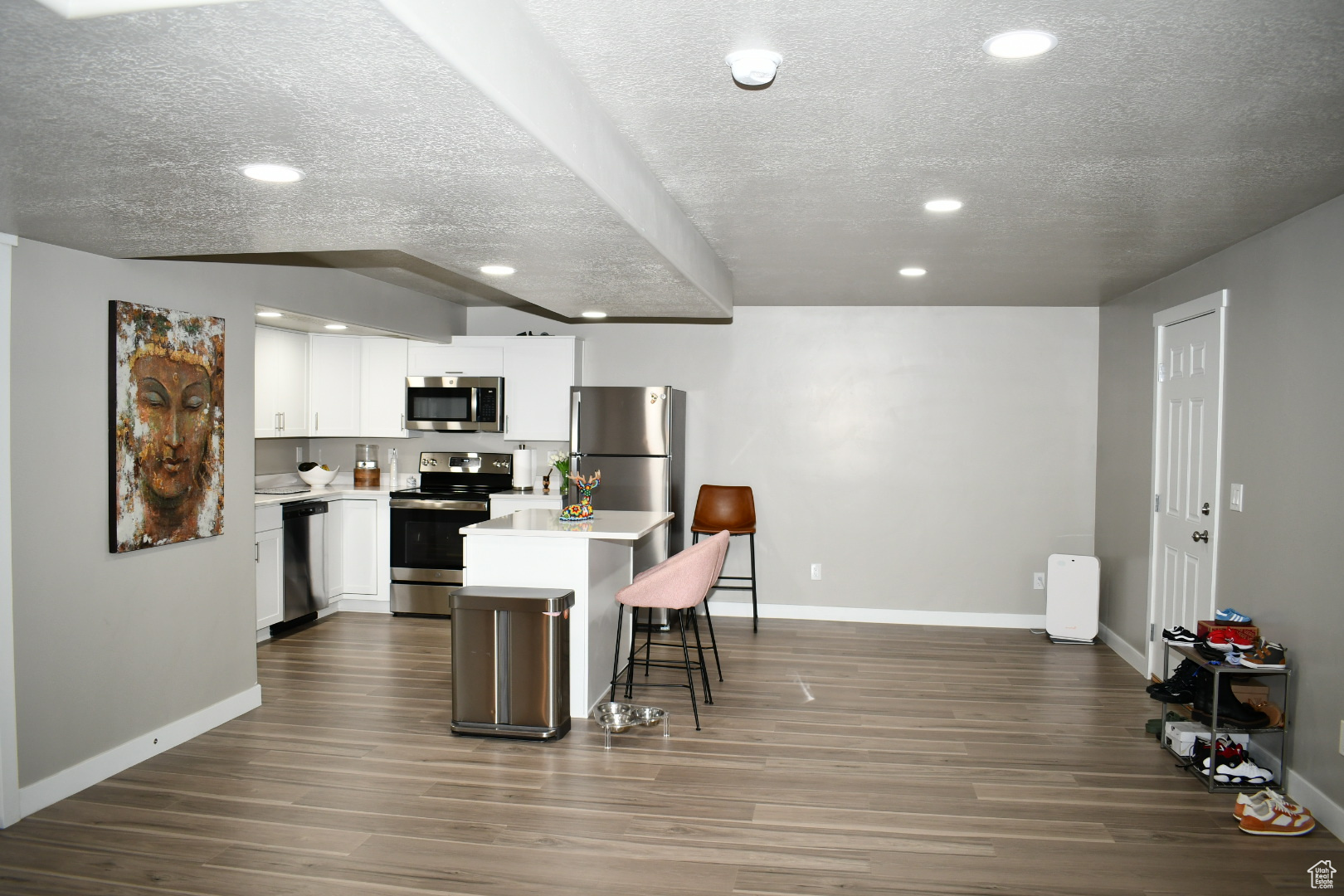 Kitchen featuring a kitchen island, appliances with stainless steel finishes, a breakfast bar area, dark wood-style flooring, and light countertops