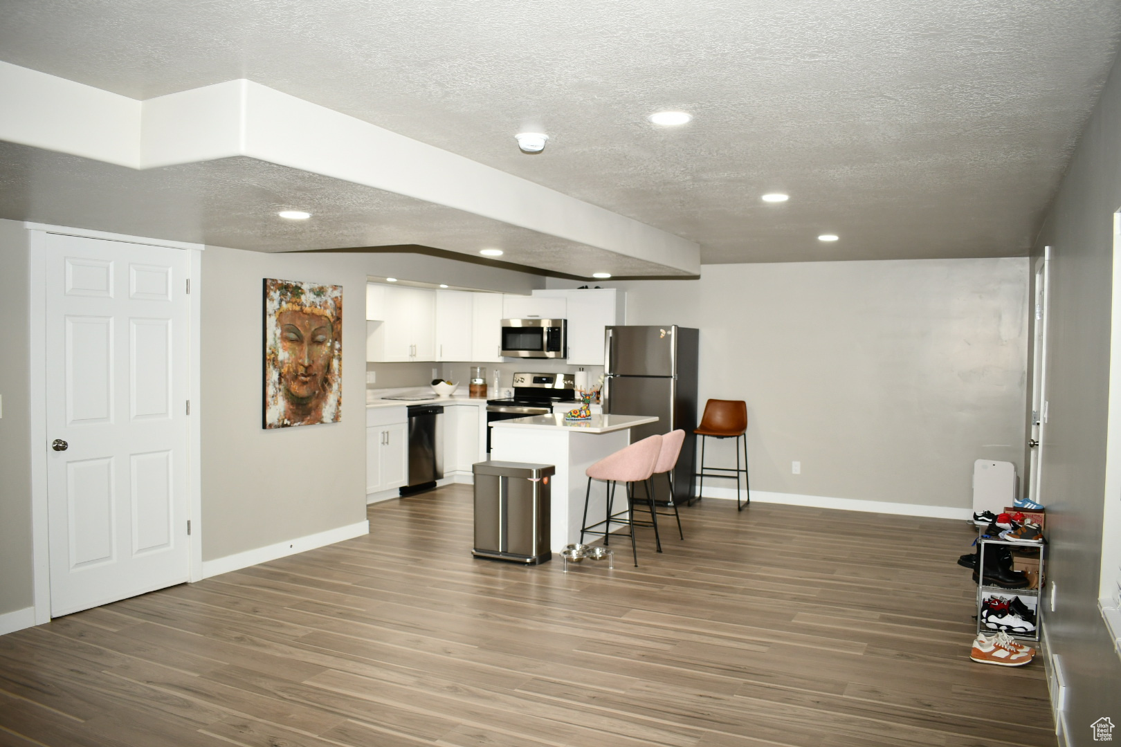 Kitchen with white cabinetry, a kitchen bar, appliances with stainless steel finishes, and wood finished floors