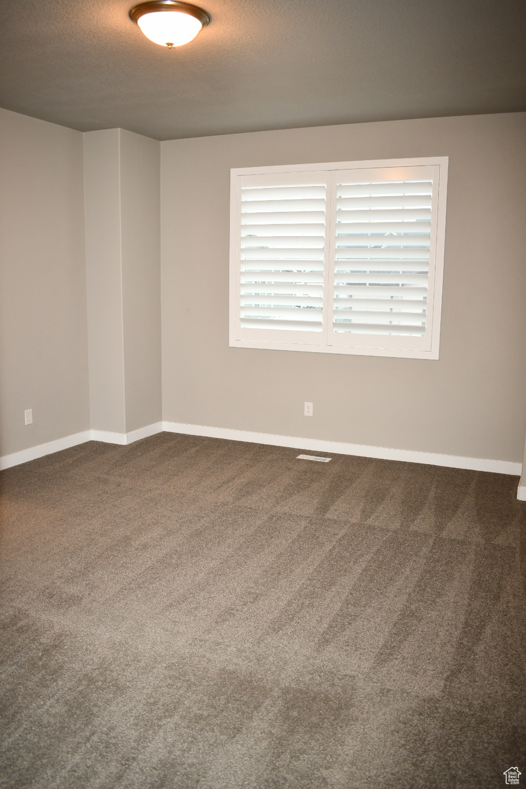 Spare room with carpet flooring, a textured ceiling, and baseboards
