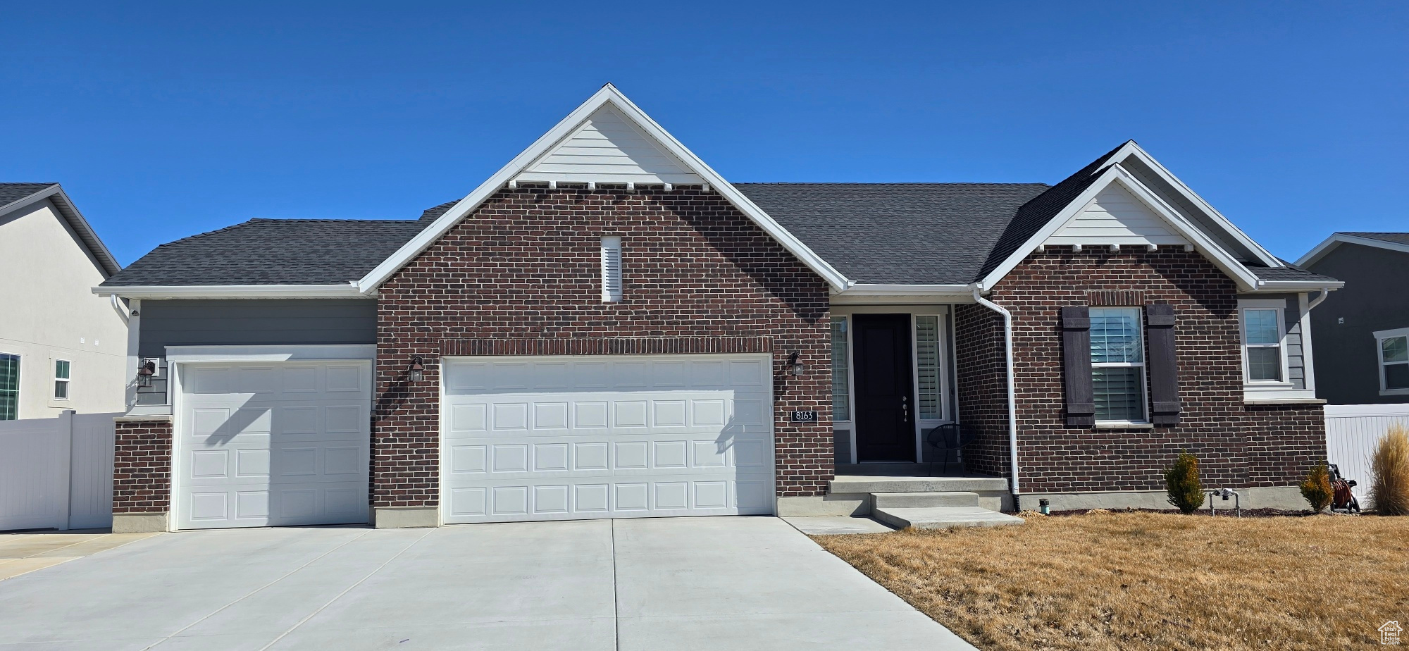 View of front facade with brick siding, driveway, an attached garage, and roof with shingles