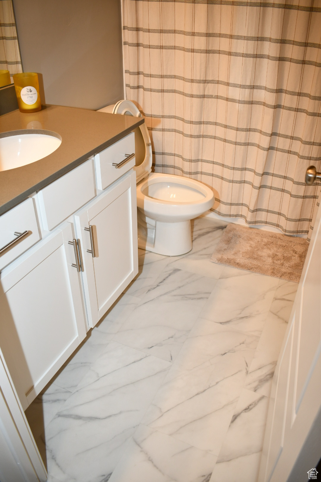 Full bathroom featuring toilet, marble finish floor, curtained shower, and vanity