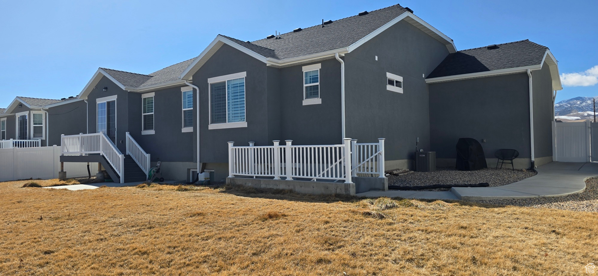Rear view of house featuring a lawn, fence, and stucco siding