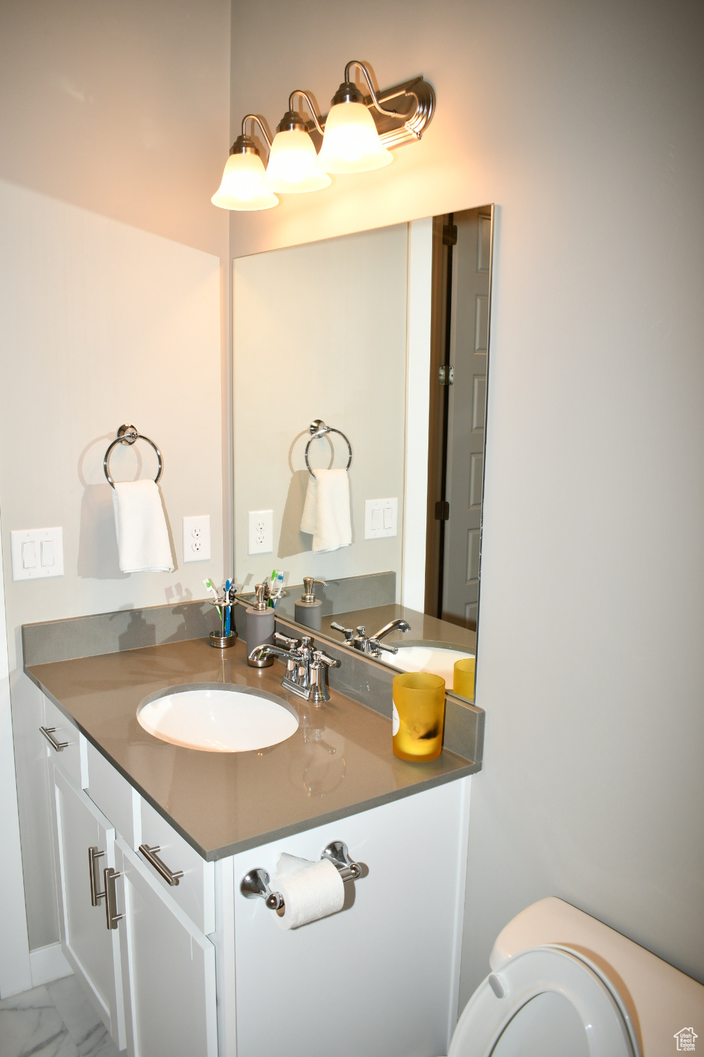 Half bathroom featuring toilet, marble finish floor, and vanity
