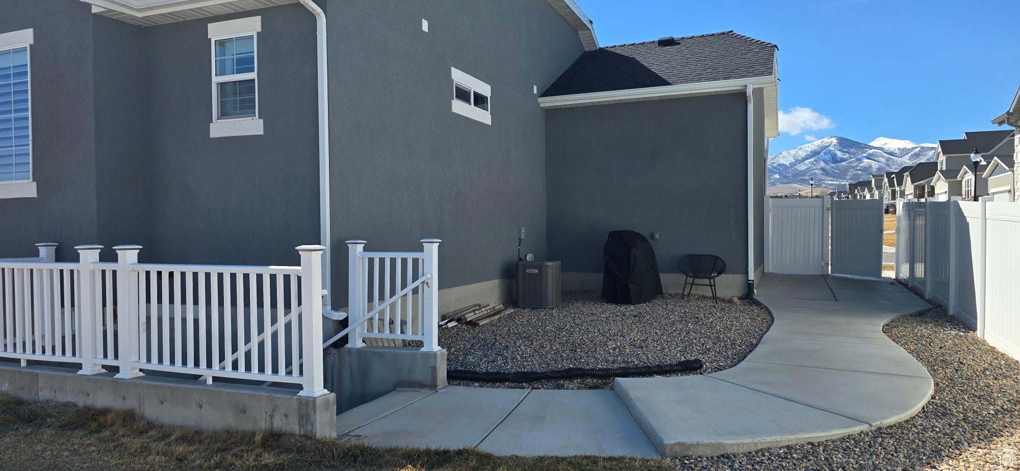 View of side of property with a mountain view, fence, and stucco siding