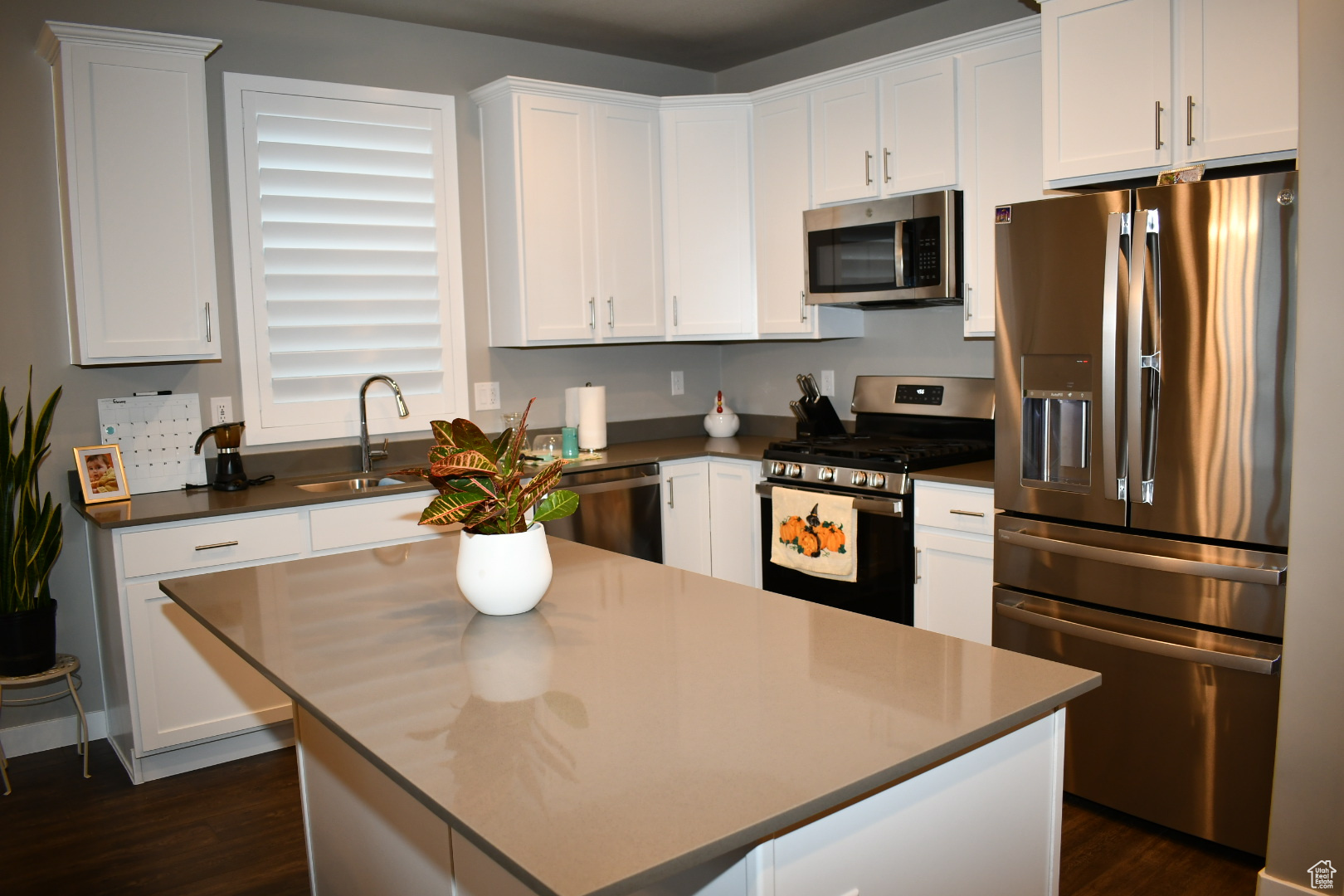Kitchen featuring appliances with stainless steel finishes, dark countertops, white cabinetry, and a sink