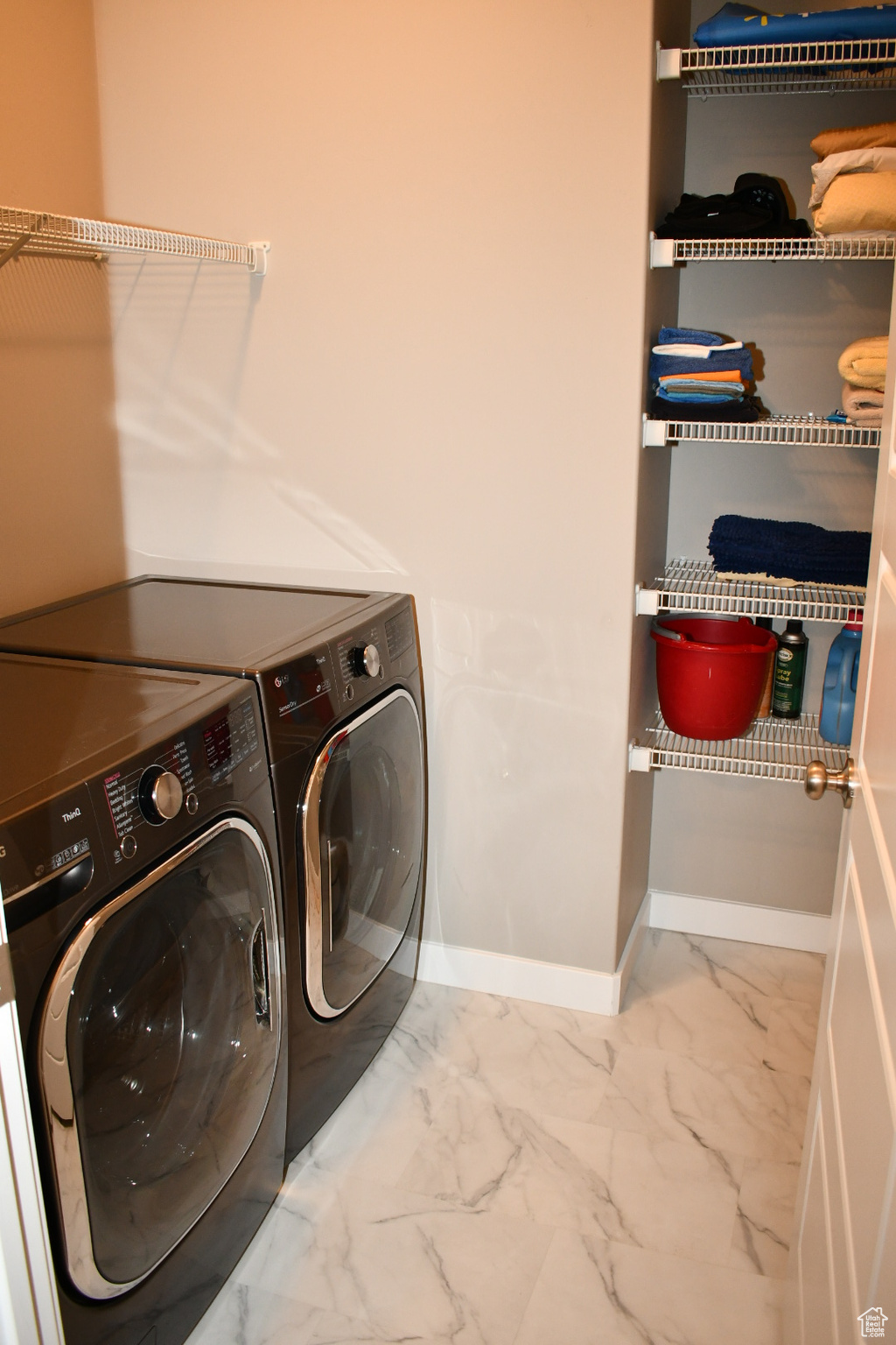 Washroom featuring marble finish floor, laundry area, baseboards, and washer and clothes dryer
