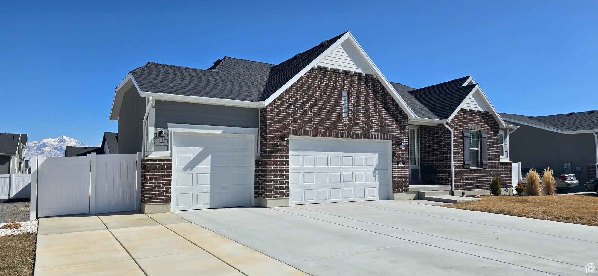 Ranch-style home with driveway, a shingled roof, an attached garage, fence, and brick siding