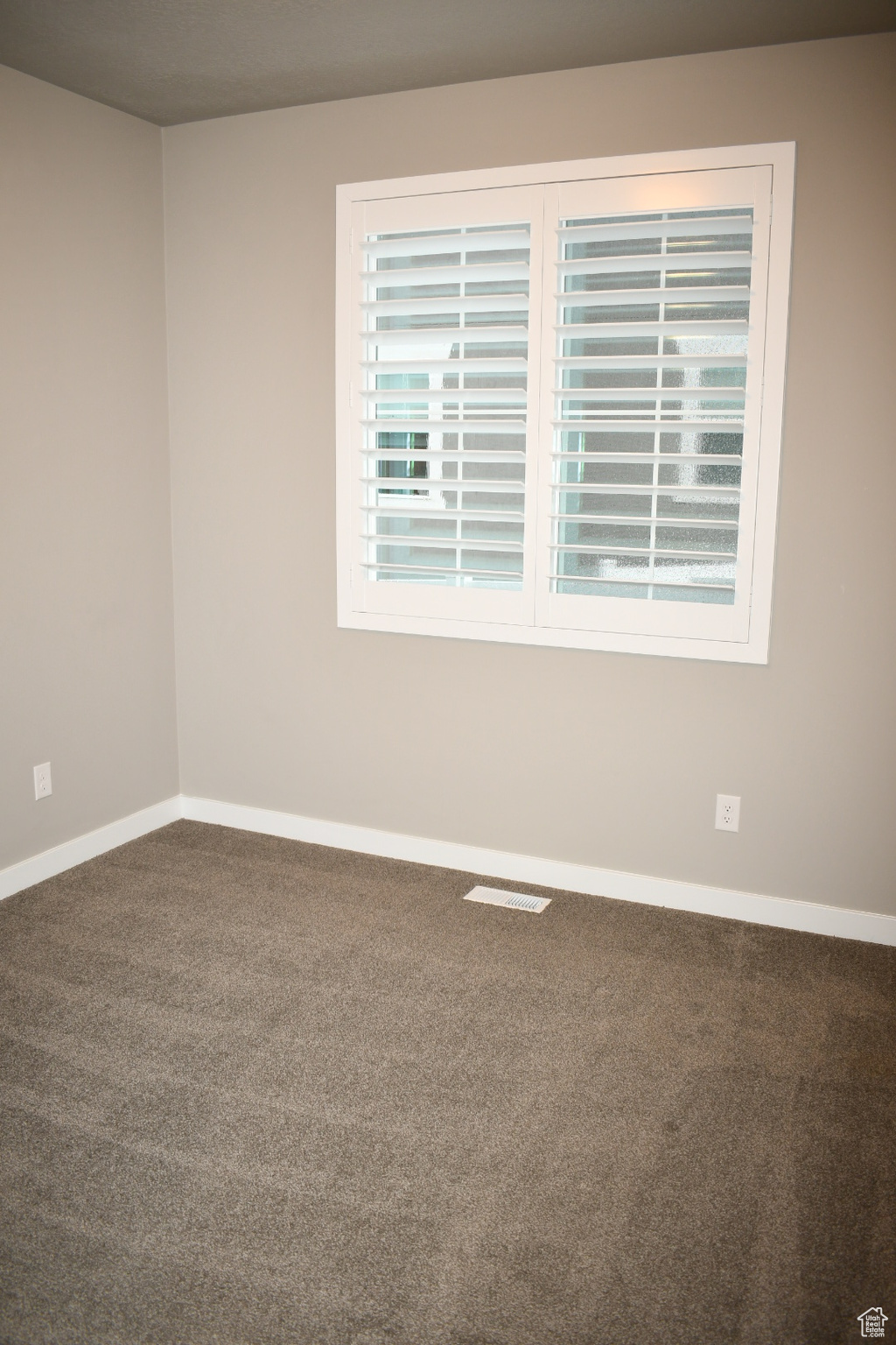 Spare room featuring carpet floors, visible vents, and baseboards