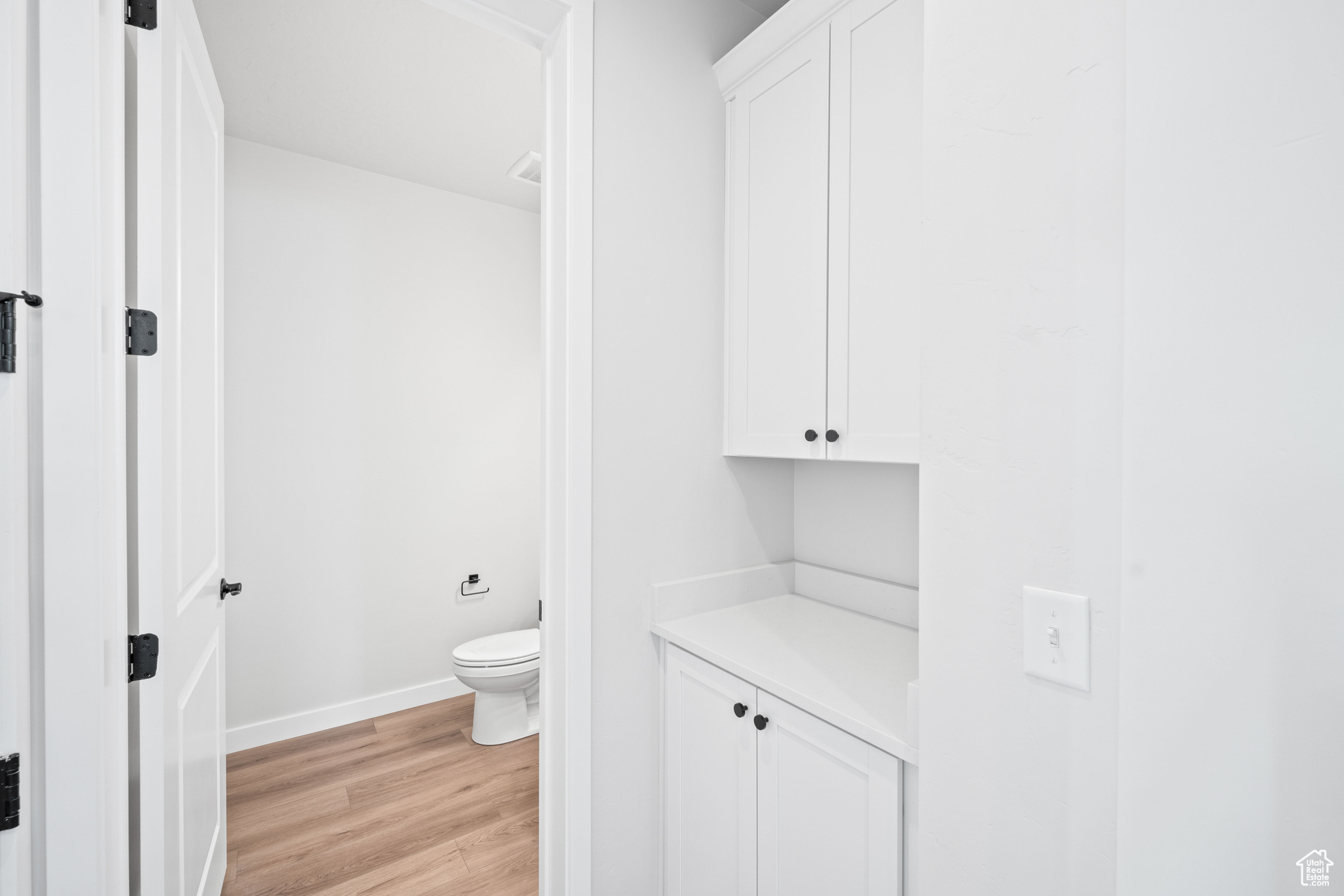 Bathroom featuring toilet, wood finished floors, and baseboards
