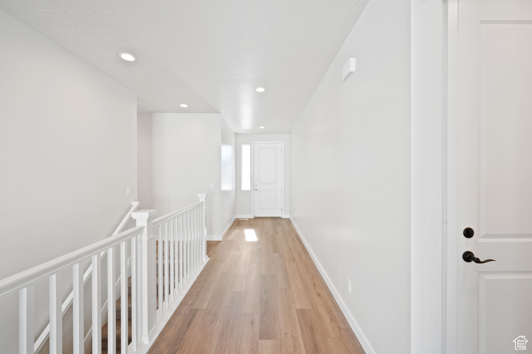 Hallway with recessed lighting, baseboards, an upstairs landing, and light wood finished floors