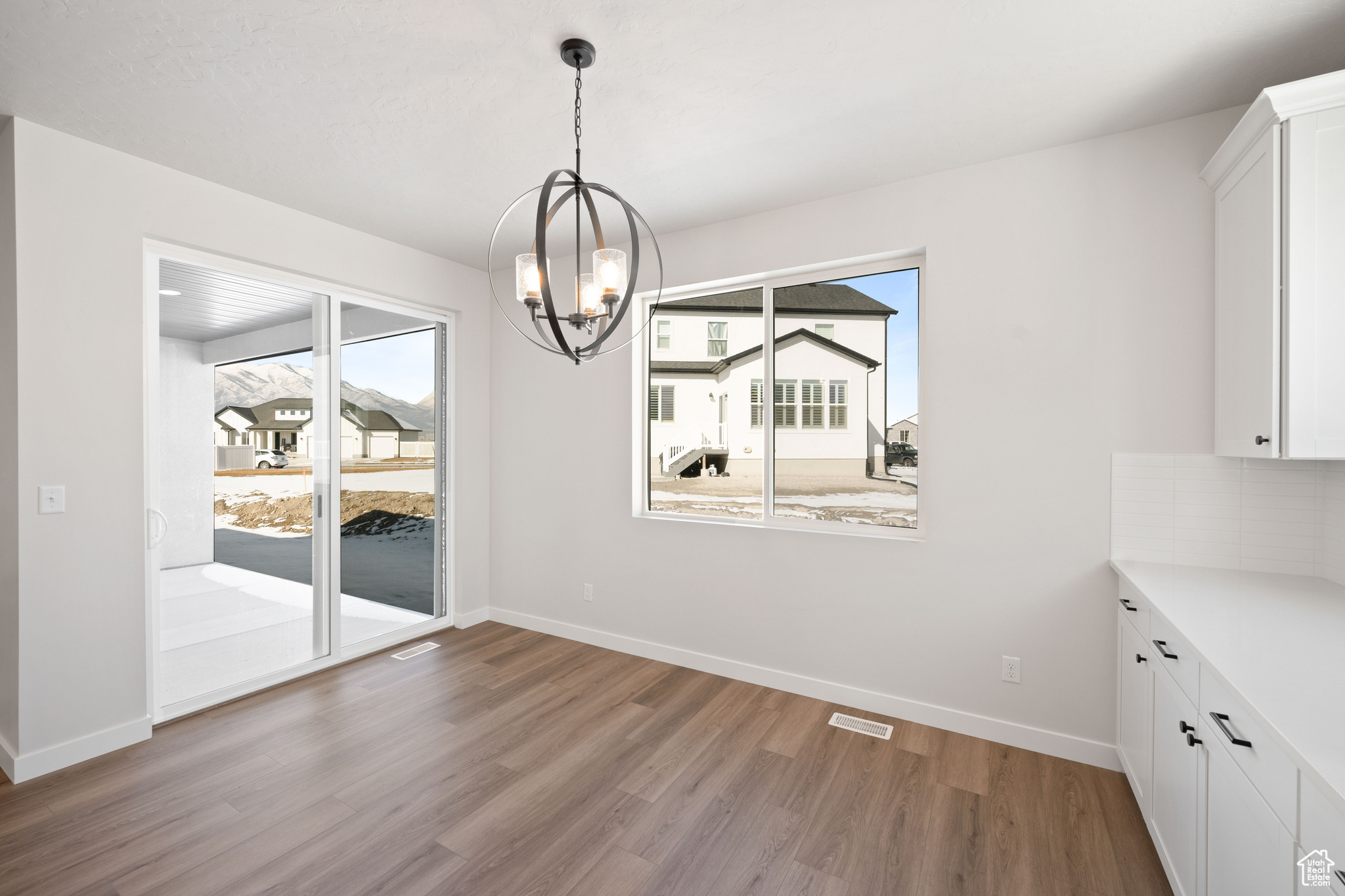 Unfurnished dining area featuring an inviting chandelier, plenty of natural light, light wood-style floors, and visible vents