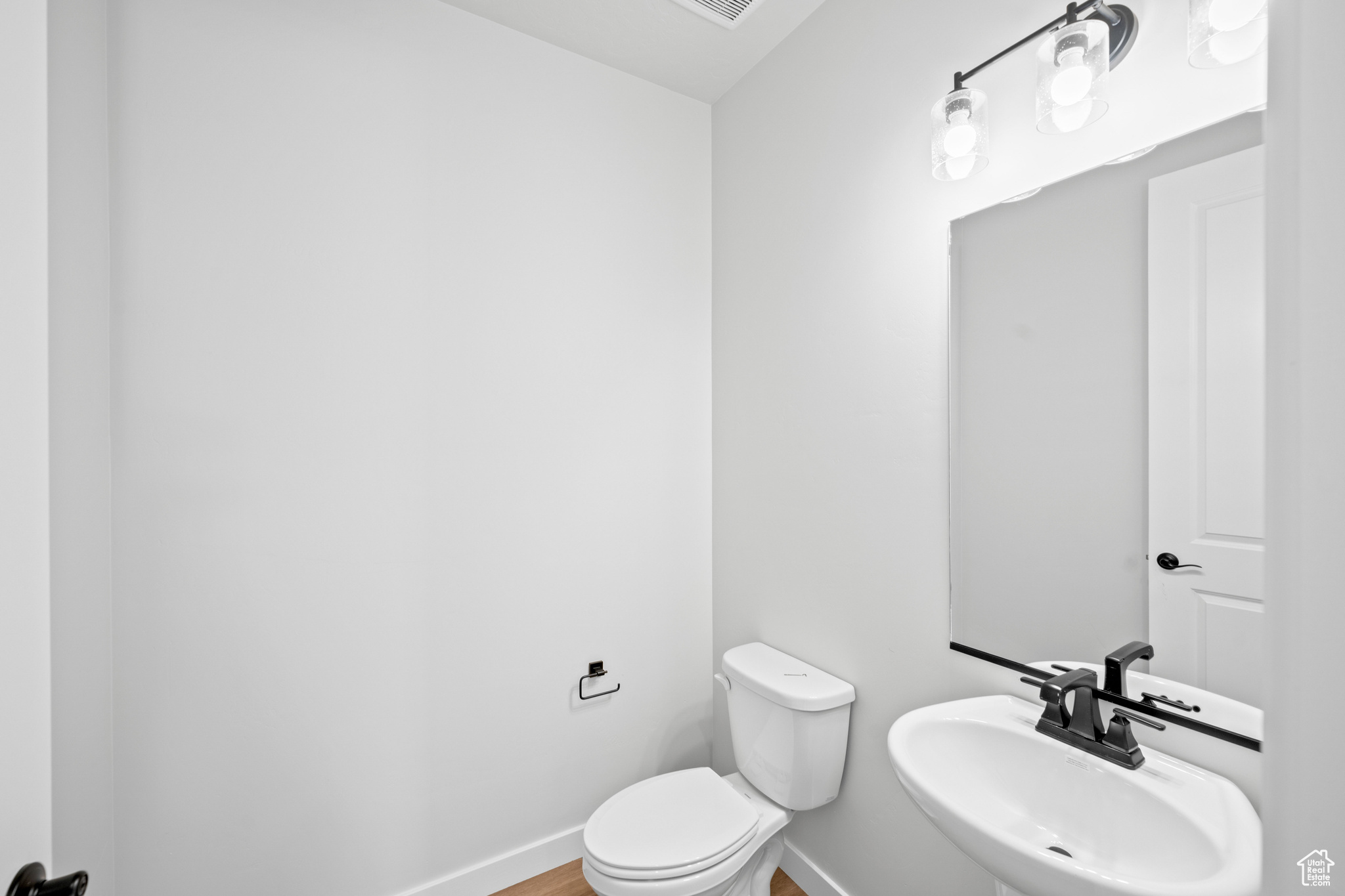 Bathroom featuring wood finished floors, toilet, baseboards, and a sink