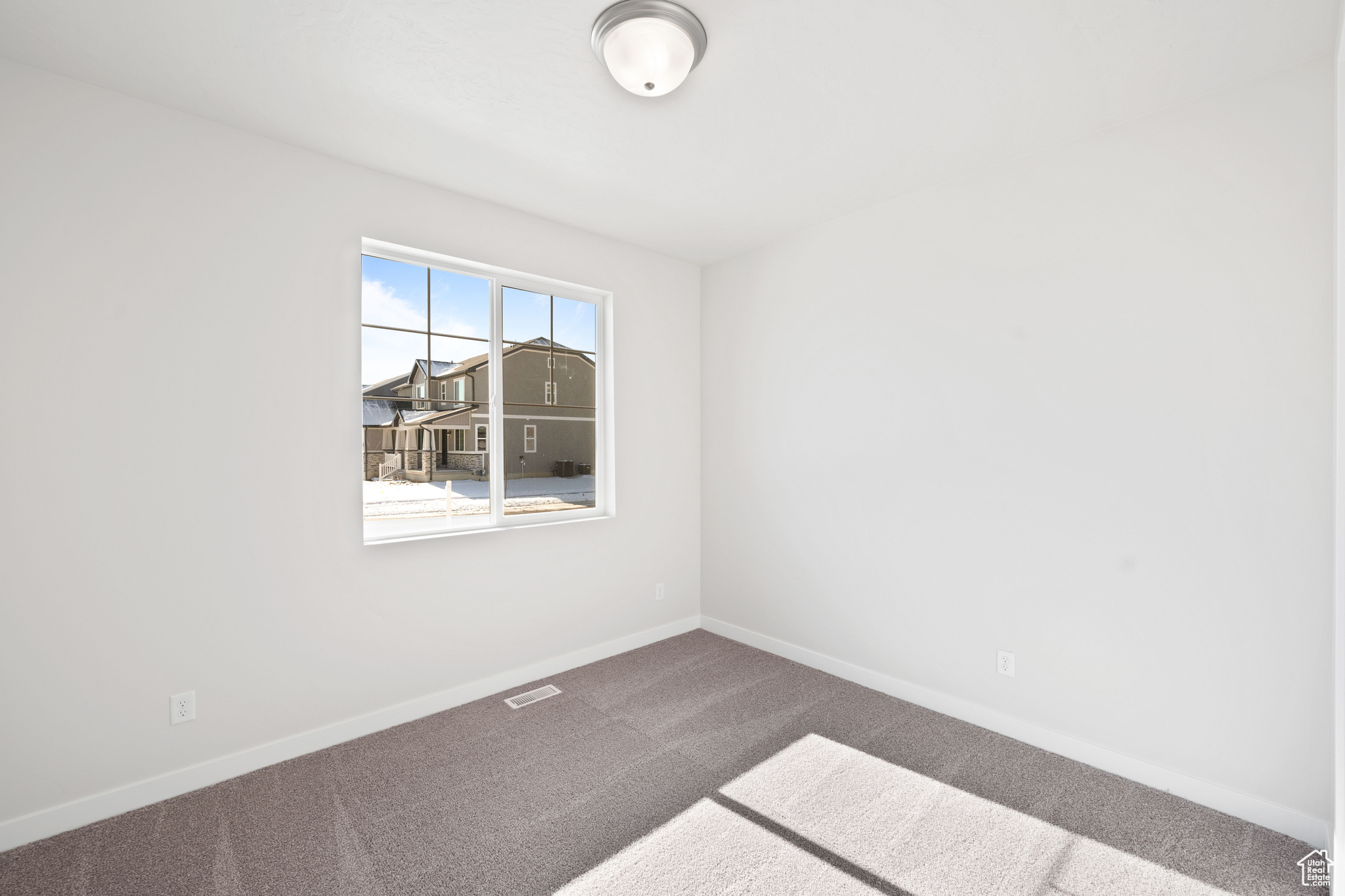 Empty room featuring carpet flooring, visible vents, and baseboards